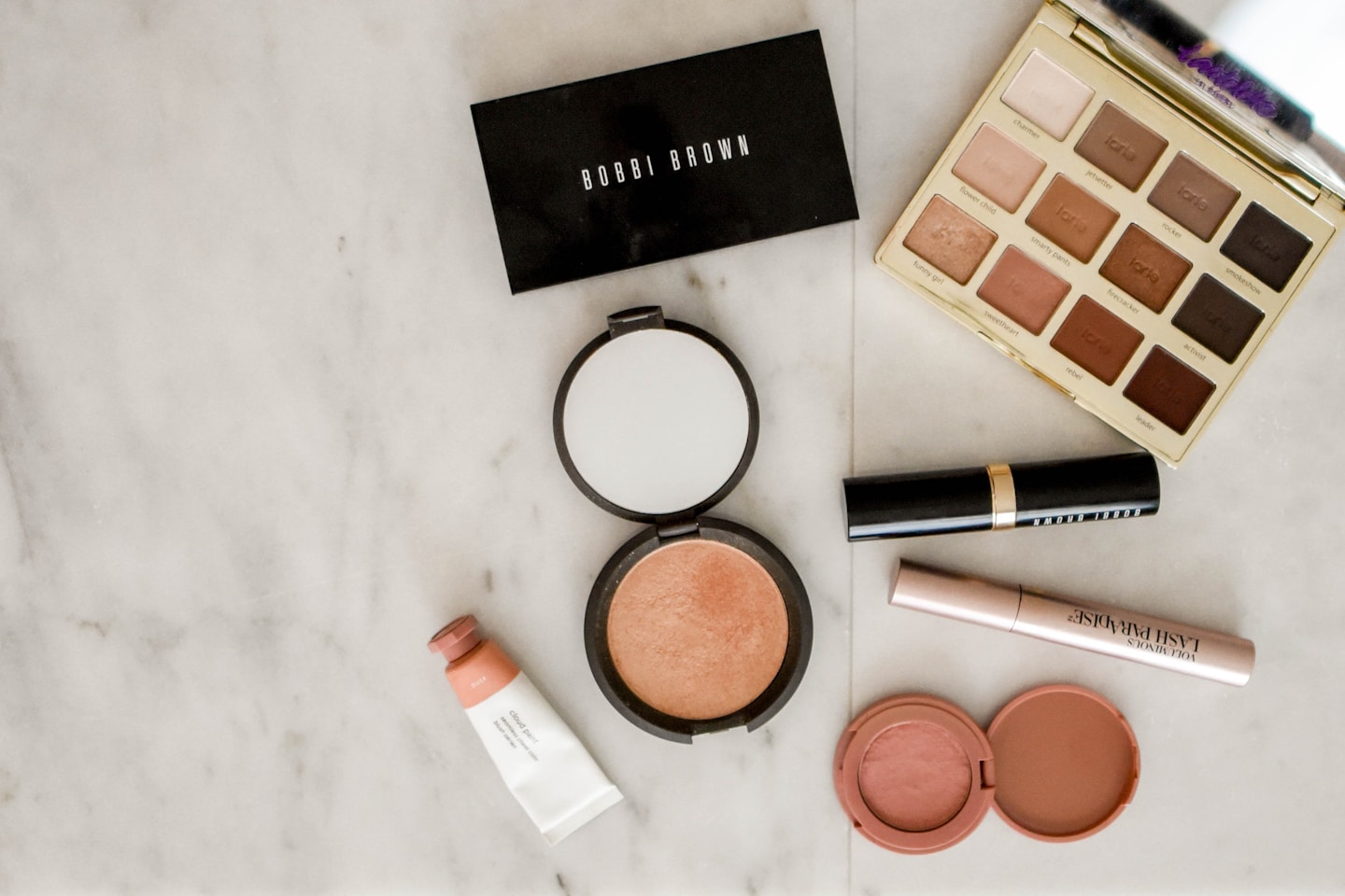 photo of assorted makeup products on gray surface